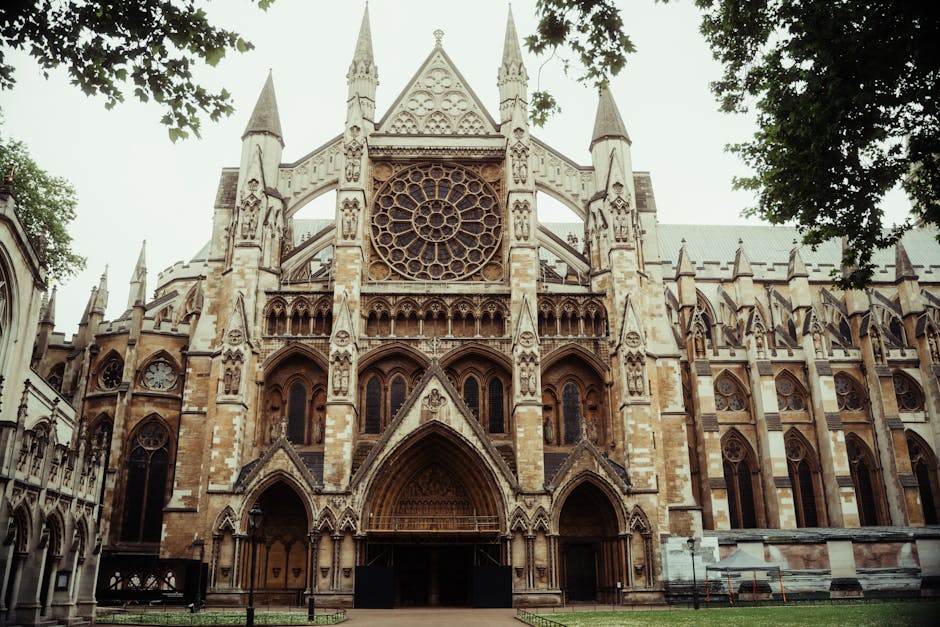 A detailed view of Westminster Abbey's Gothic architecture, featuring two prominent square towers with pointed spires and ornate stone carvings. The clock faces on the towers are visible, with one sho